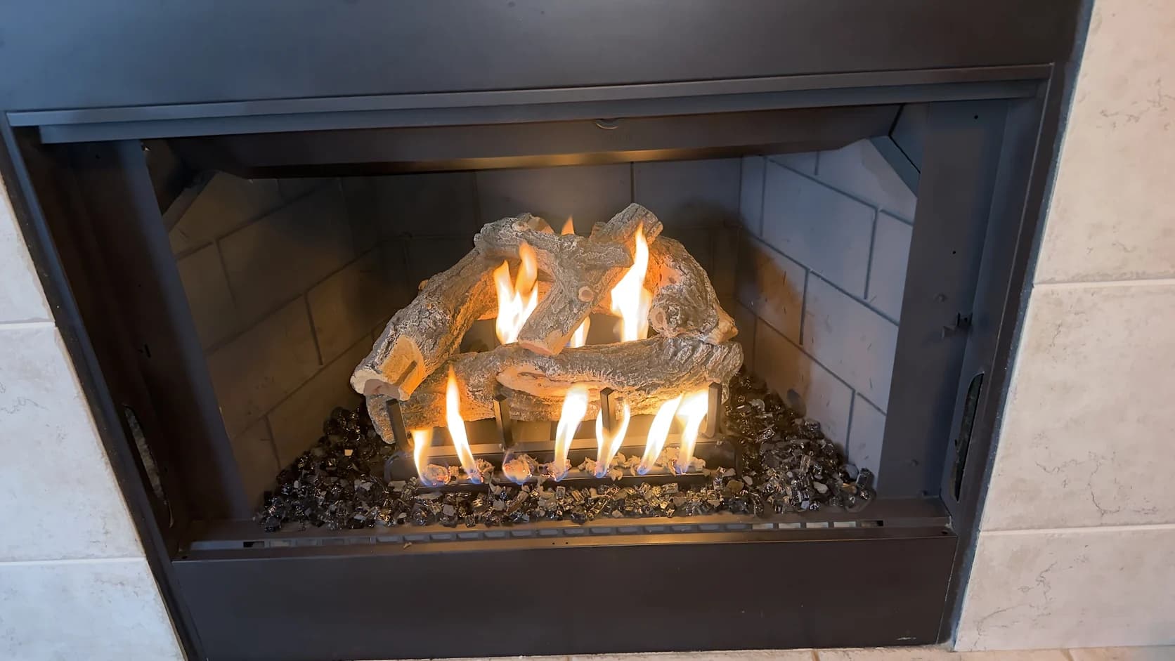 Gas log set burning in a black metal firebox