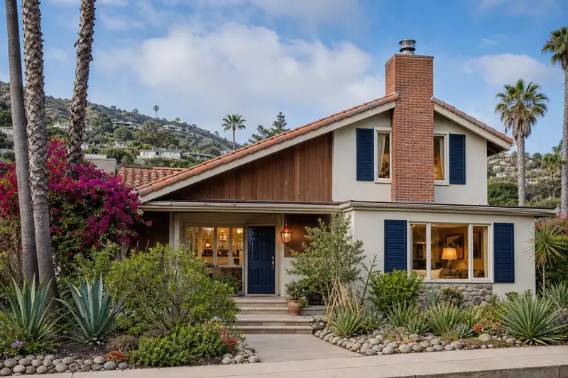 A 1970s coastal contemporary house in soft daylight with a used-brick chimney with a spark arrestor cap and even brickwork; illustrative image