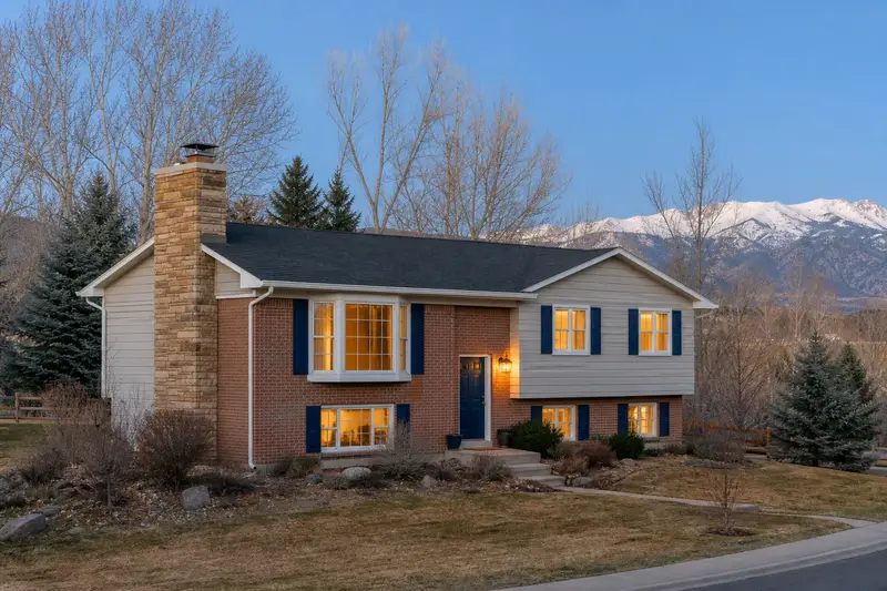 A 1990s split-level house with brick and siding with a sandstone chimney with a spark arrestor cap and neat mortar joints; illustrative image