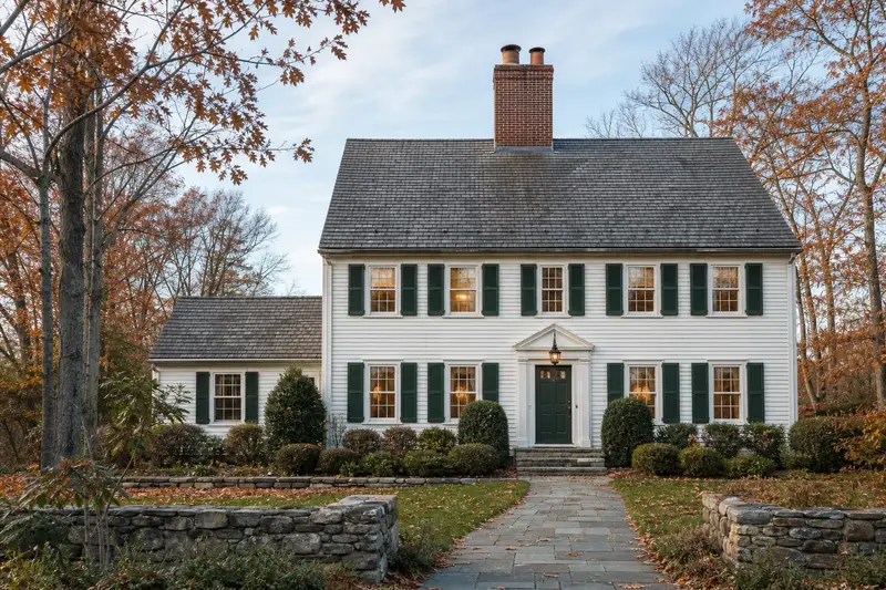 A 1990s two-story suburban house with a two-flue brick chimney on a slate roof and a tidy front walk; illustrative image