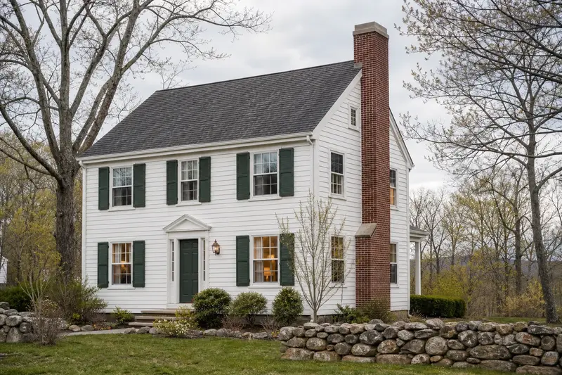 A 1950s white clapboard colonial with a red brick chimney with a concrete crown and neat mortar joints; illustrative image