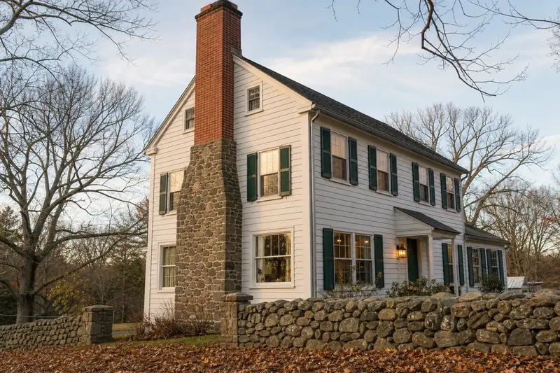 A 1950s colonial with a fieldstone chimney with a stone masonry chimney of clean red brick; illustrative image