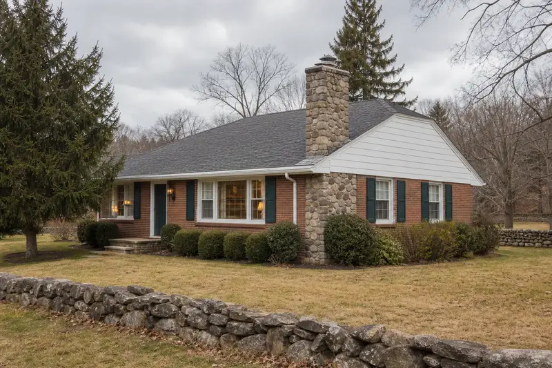 A 1970s brick-front ranch house with a stone masonry chimney topped by a new stainless steel cap; illustrative image