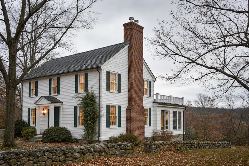 A 1940s white clapboard colonial with a two-flue brick chimney on a slate roof fitted with a stainless steel liner cap; illustrative image