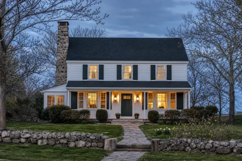 A 1960s two-story suburban house with a stone masonry chimney rising above the roof; illustrative image