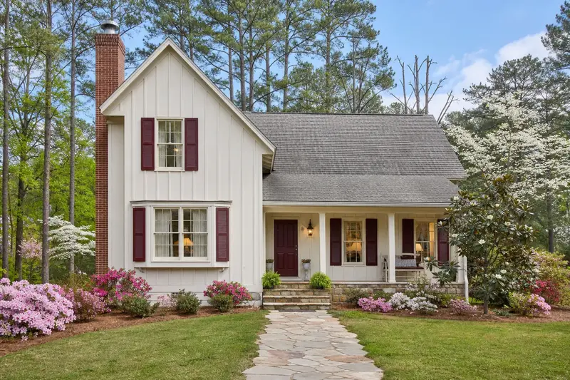 A 1970s farmhouse-style house with board-and-batten siding with an exterior end brick chimney on a gable roof and a stainless steel cap; illustrative image