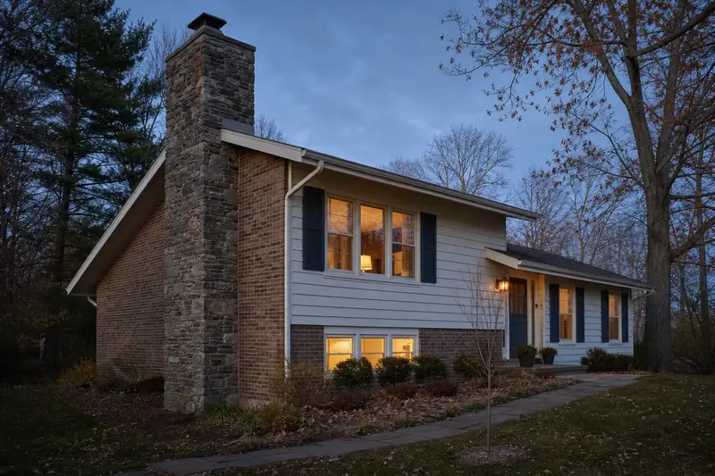A 1960s split-level house with a stone masonry chimney and a tidy front walk; illustrative image
