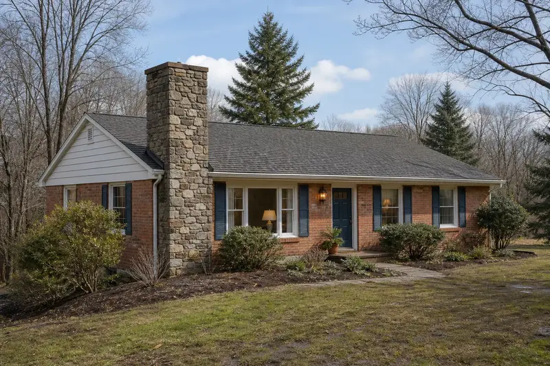A 1970s brick-front ranch house showing a stone masonry chimney rising above the roof; illustrative image