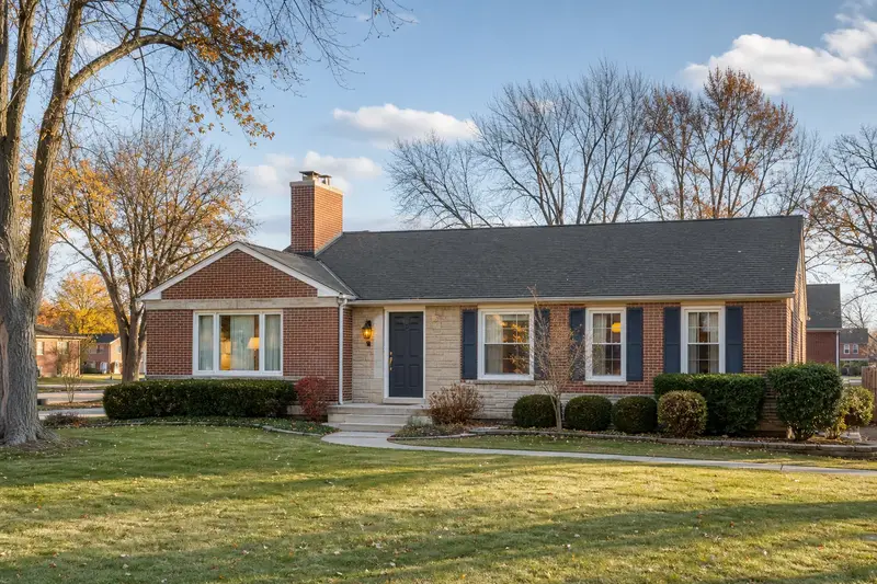 A 1980s brick-front ranch house in soft daylight with a red brick chimney with a concrete crown standing clear above the roofline; illustrative image