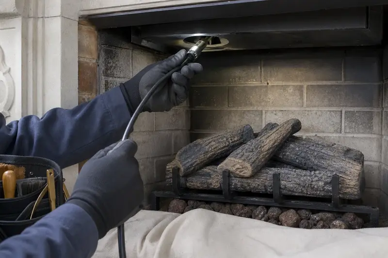 An inspection camera head on a flexible cable at the damper opening of a vented gas log set in a masonry firebox; illustrative image