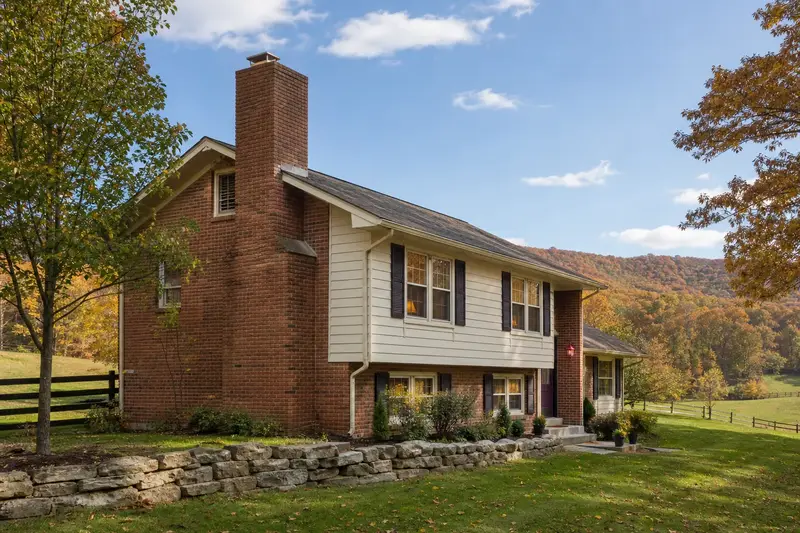 A 1970s split-level house with brick and siding with an exterior end brick chimney on a gable roof rising above the roof; illustrative image