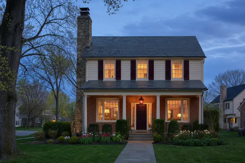 A 1980s two-story suburban house with a front porch with a fieldstone chimney with a metal cap rising above the roof; illustrative image