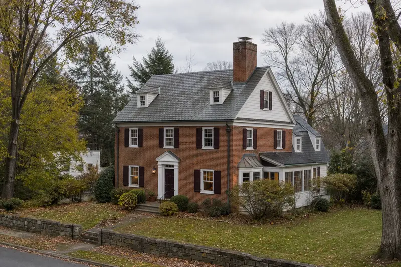 A 1920s brick colonial with shutters with a brick chimney with a stainless steel cap and period details; illustrative image