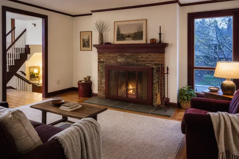 A hearth room with an open masonry wood-burning fireplace, a clear hearth and soft window light; illustrative image