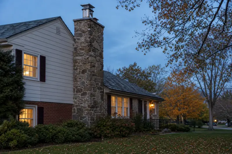A 1960s split-level house with brick and siding with a fieldstone chimney with a metal cap and a stainless steel cap; illustrative image