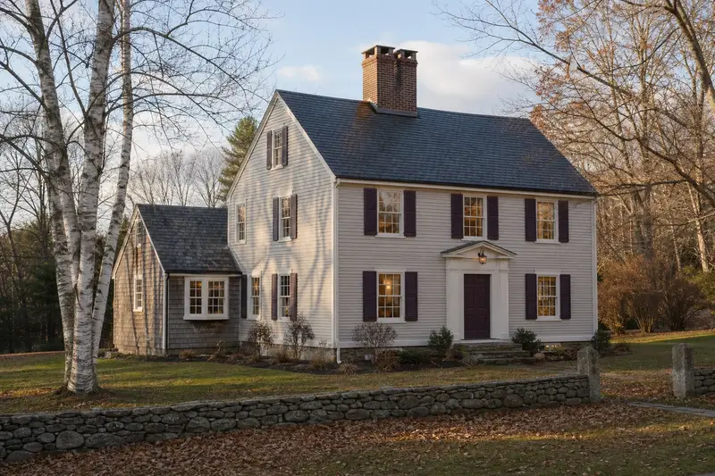 A 1940s clapboard colonial in soft daylight with a two-flue brick chimney on a slate roof and even brickwork; illustrative image