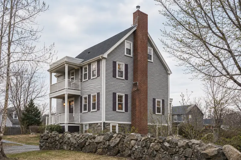 A 1950s triple-decker house with a tall brick chimney on a steep gable roof fitted with a stainless steel liner cap; illustrative image