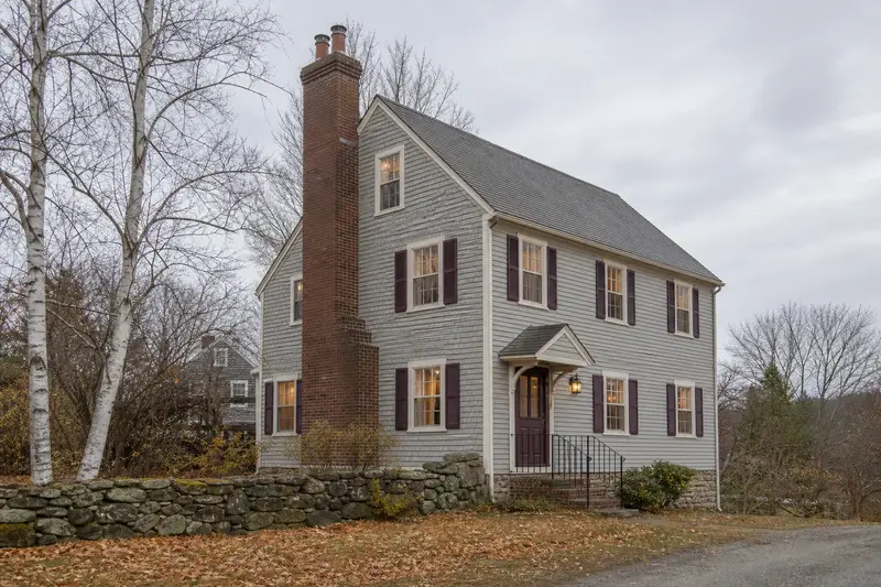 A 1950s triple-decker house with a two-flue brick chimney on a slate roof and neat mortar joints; illustrative image