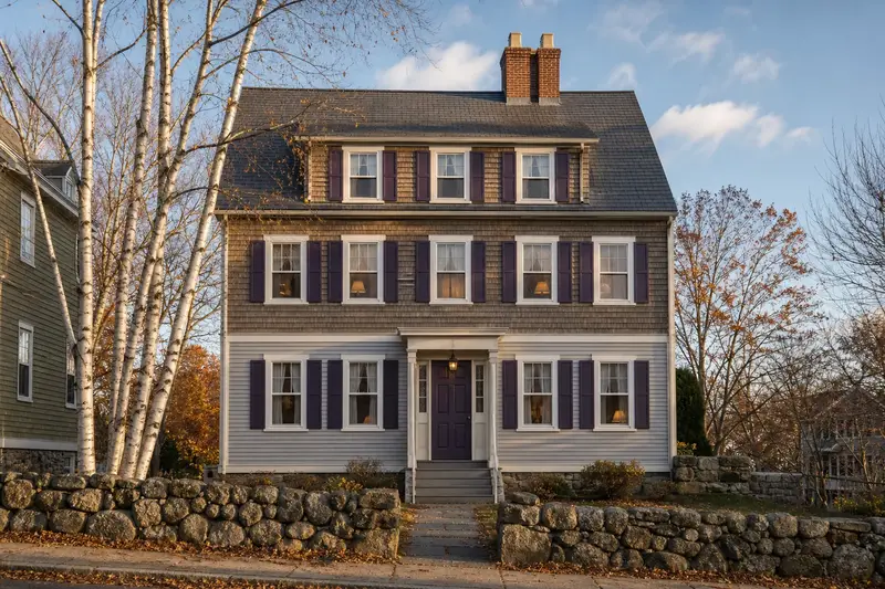 A 1950s triple-decker house with a two-flue brick chimney on a slate roof and neat mortar joints; illustrative image