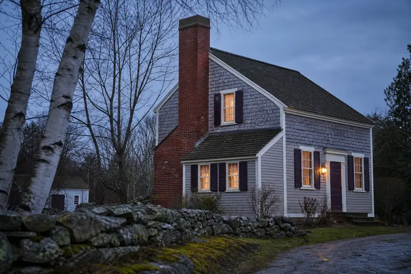 A 1950s saltbox house seen from the street with a red brick chimney with a concrete crown; illustrative image
