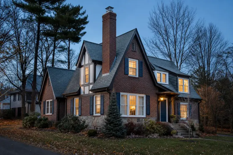 A 1950s Tudor revival house with a tall brick chimney on a steep gable roof and a stainless steel cap; illustrative image