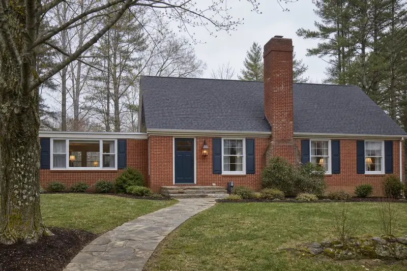 A 1960s brick-front ranch house with a tall brick chimney on a steep gable roof of even red brick; illustrative image