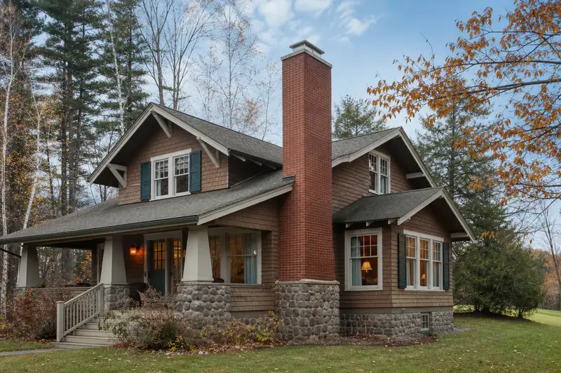 A 1950s Craftsman house in soft daylight with a red brick chimney with a concrete crown standing clear above the roofline; illustrative image