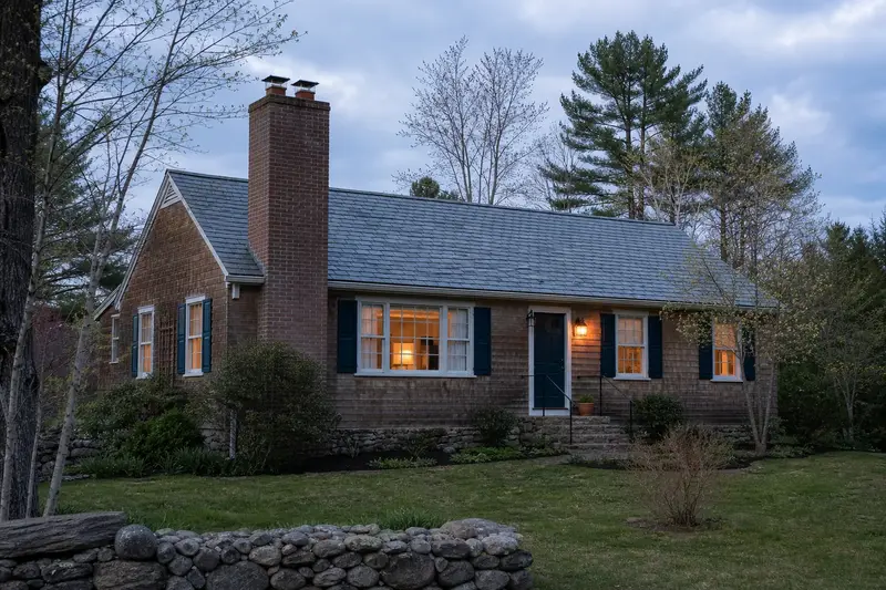 A 1950s cedar-sided rambler with a two-flue brick chimney on a slate roof and neat, even mortar joints; illustrative image