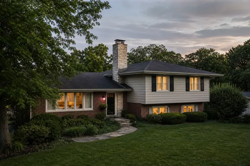 A 1960s split-level house with brick and siding in soft daylight with a limestone chimney with a metal cap standing clear above the roofline; illustrative image