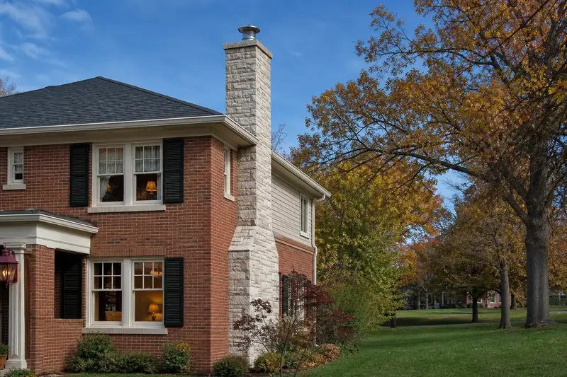 A 1930s brick foursquare house with a limestone chimney with a metal cap topped by a new stainless steel cap; illustrative image