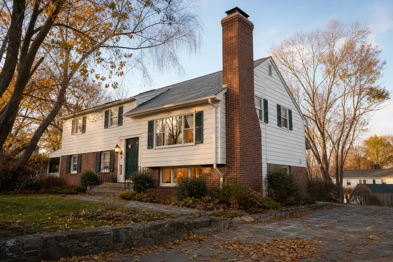 A 1960s split-level house with a tall brick chimney on a steep gable roof and neat mortar joints; illustrative image