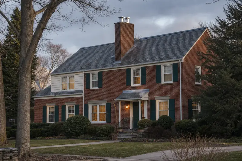 A 1950s brick twin home with a two-flue brick chimney on a slate roof topped by a new stainless steel cap; illustrative image