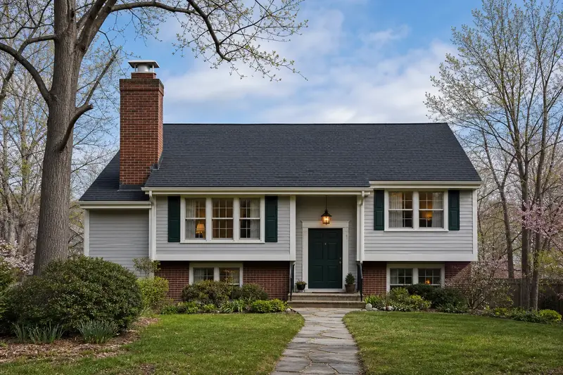 A 1990s split-level house with a tall brick chimney on a steep gable roof topped by a new stainless steel cap; illustrative image