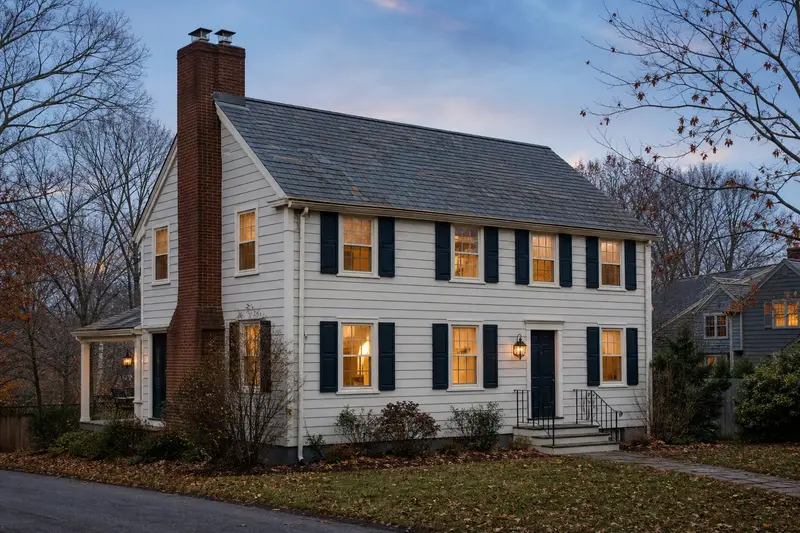 A 1970s two-story suburban house with a two-flue brick chimney on a slate roof and a stainless steel cap; illustrative image