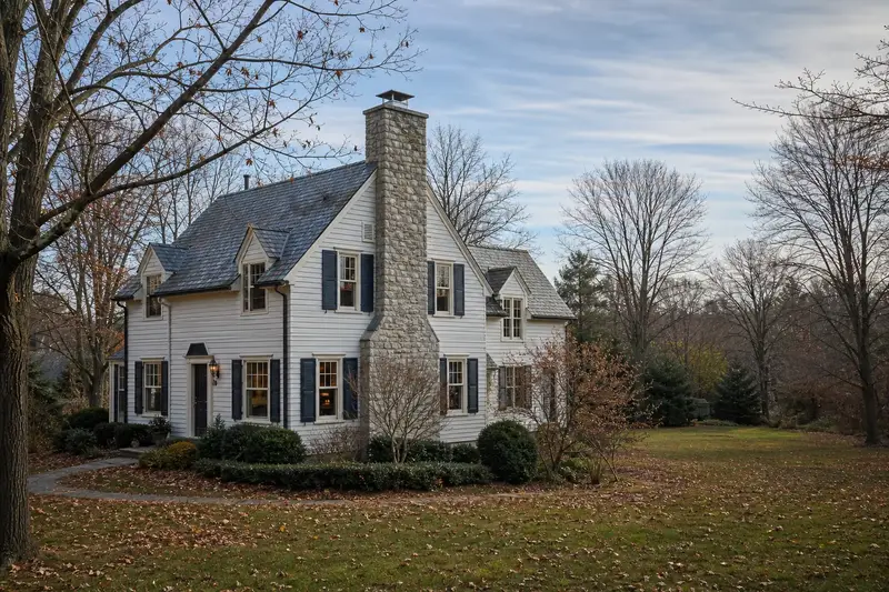 A 1940s steep-gabled frame house with a stone masonry chimney topped by a new stainless steel cap; illustrative image