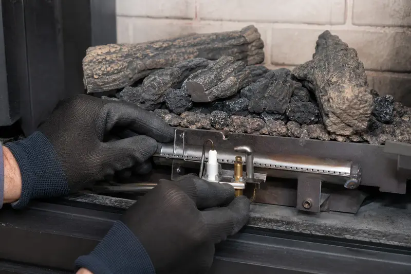 The burner, pilot assembly and ember bed inside a direct-vent gas fireplace, unlit, seen up close; illustrative image