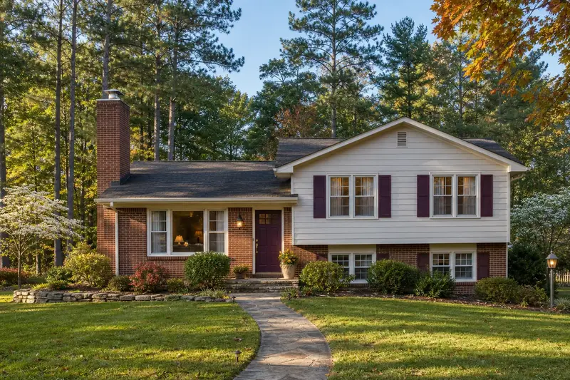 A 1990s brick-and-siding split-level house with an exterior end brick chimney on a gable roof topped by a new stainless steel cap; illustrative image
