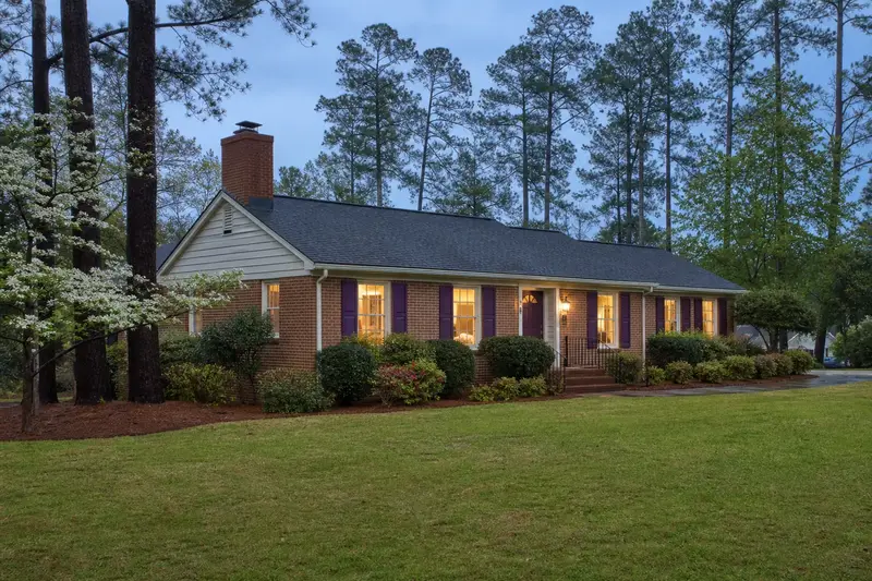 A 1990s brick ranch house with a red brick chimney with a concrete crown on an asphalt shingle roof and neat mortar joints; illustrative image
