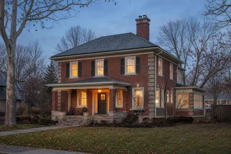 A 1950s brick foursquare house with a two-flue brick chimney on a slate roof and a stainless steel cap; illustrative image