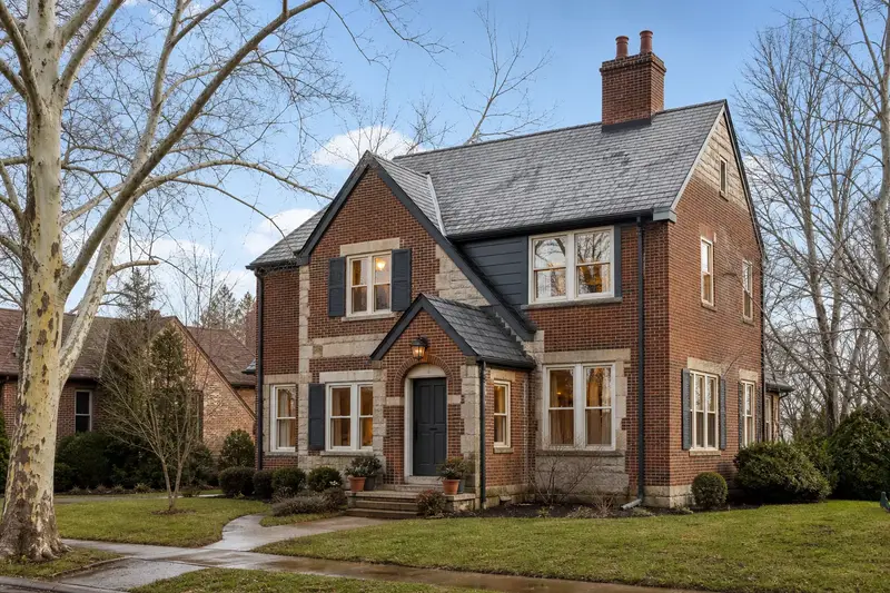 A 1940s brick-and-sandstone house with a two-flue brick chimney on a slate roof and neat mortar joints; illustrative image