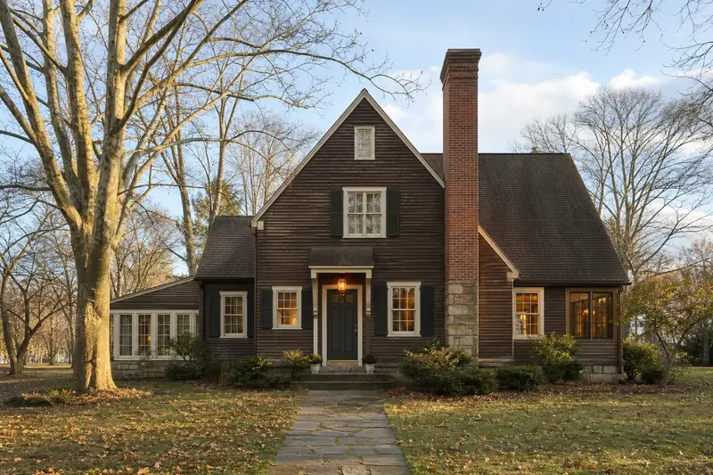 A 1980s cedar-sided contemporary house with a tall brick chimney on a steep gable roof rising above the roof; illustrative image