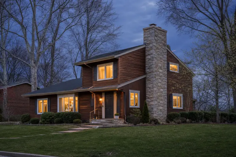 A 1980s cedar-sided contemporary house with a stone masonry chimney and neat mortar joints; illustrative image