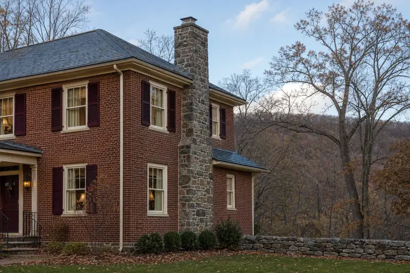 A 1950s brick foursquare house with a stone masonry chimney and neat, even mortar joints; illustrative image