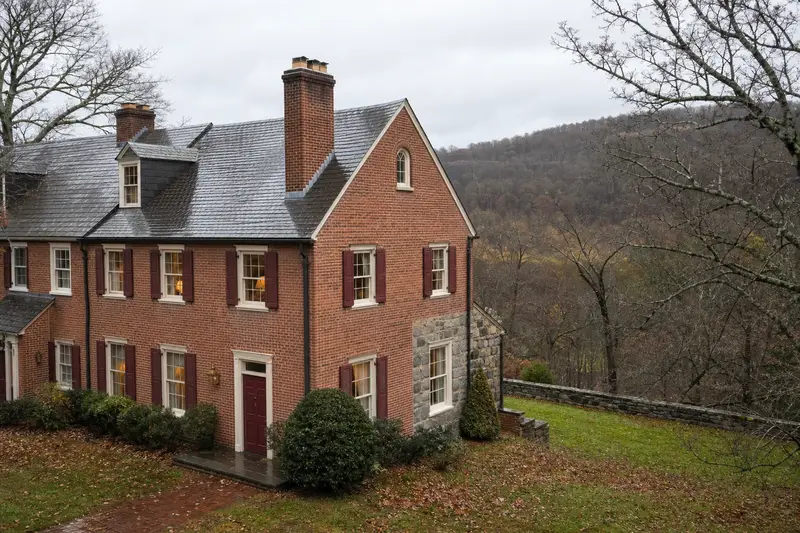 A 1940s brick rowhouse after a cold rain with a tall brick chimney on a steep gable roof, wet roofs and clear gutters; illustrative image