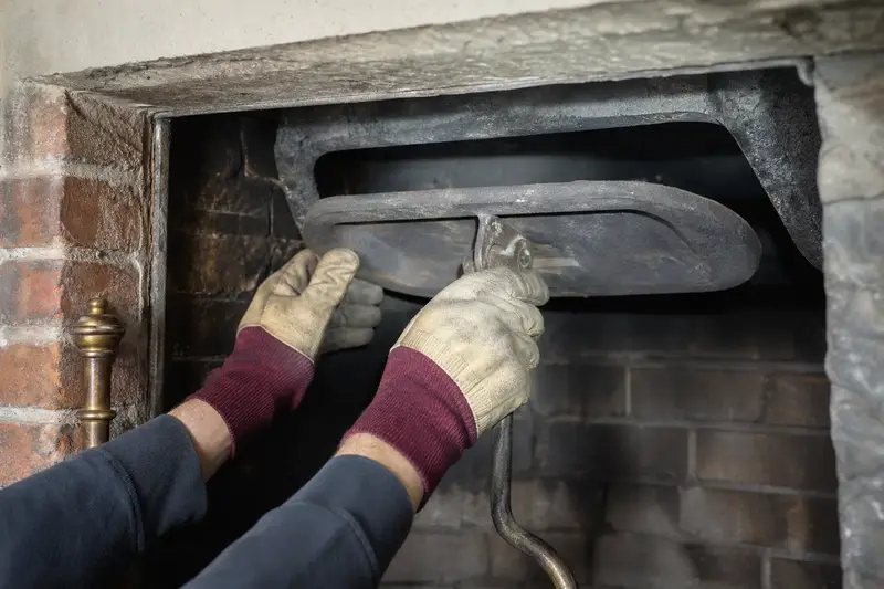 Gloved hands working a cast-iron damper plate inside a cold masonry firebox; illustrative image