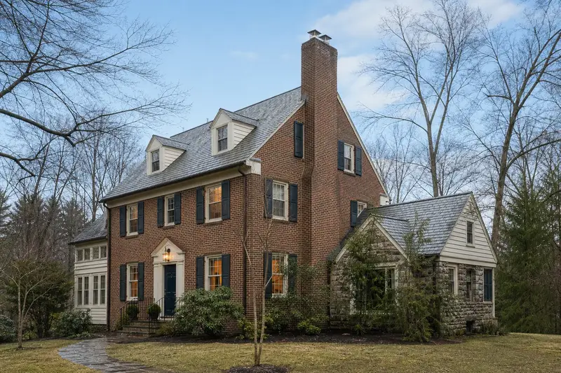 A 1940s brick colonial with a two-flue brick chimney on a slate roof topped by a stainless steel cap; illustrative image