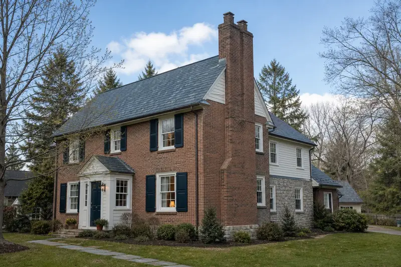 A 1940s brick colonial in soft daylight with a two-flue brick chimney on a slate roof and even brickwork; illustrative image