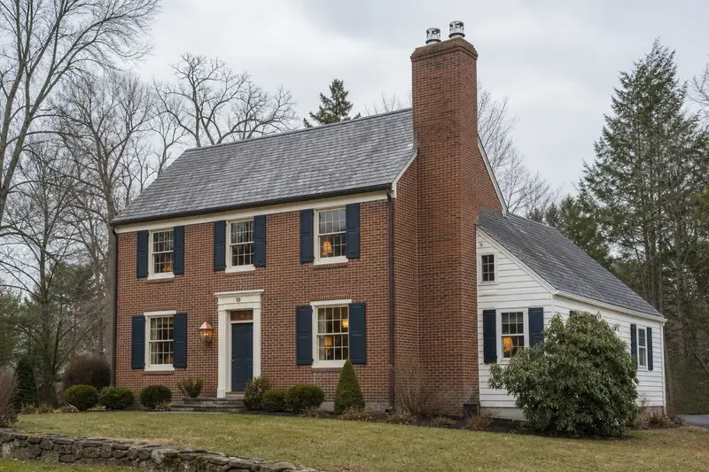 A 1940s brick colonial with a two-flue brick chimney on a slate roof fitted with a stainless steel liner cap; illustrative image