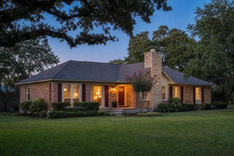 A 1980s brick ranch house with a hip roof with a stone-veneer chimney with a steel cap and a stainless steel cap; illustrative image