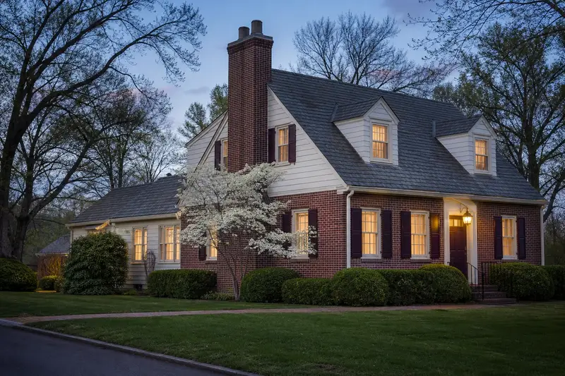 A 1940s brick-and-clapboard Cape Cod-style house with a two-flue brick chimney with a concrete crown on a slate roof rising above a steep roof; illustrative image